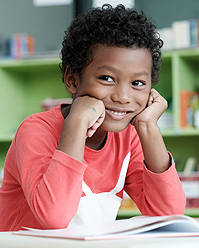 Child Smiling and Reading Book